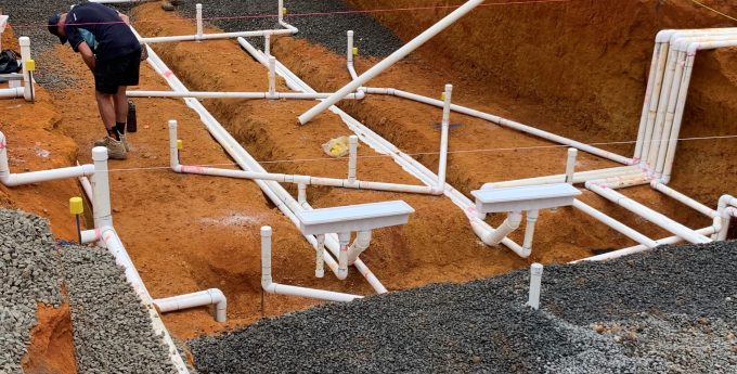 Pre-plumbing stage for an inground pool by NCS, showing the laying of necessary plumbing lines before concrete is poured.